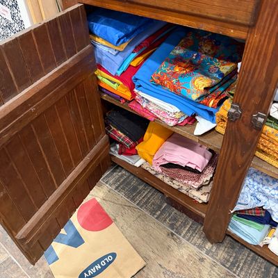 Sale Photo Thumbnail #55: Assorted colorful fabric remnants and sewing materials organized inside a rustic wooden cabinet.