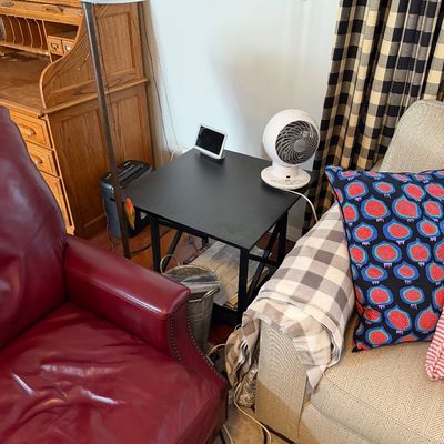 Sale Photo Thumbnail #208: Modern black metal end table with a lower shelf, shown holding a small digital display and a white Vornado personal fan.