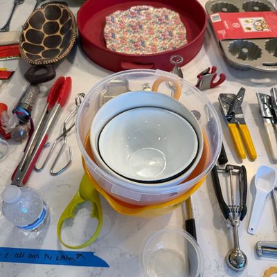 Sale Photo Thumbnail #131: Assorted kitchenware and utensils, including mixing bowls, a red serving tray, baking pans, tongs, and an ice cream scoop, arranged on a white countertop.
