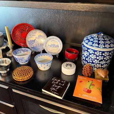 Sale Photo Thumbnail #191: Collection of decorative items including blue and white transferware plates and bowls, a lidded ceramic jar, a red lacquer plate, and various small trinkets displayed on a dark wood shelf.
