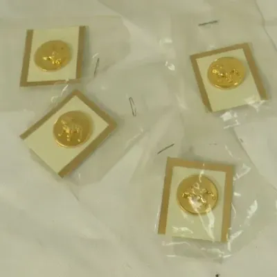 Four gold-tone round lapel pins featuring embossed animal motifs, individually packaged in original plastic sleeves.