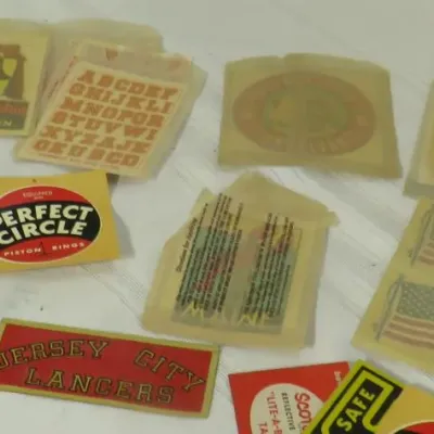 Collection of vintage decals and stickers, including a Perfect Circle Piston Rings decal, Jersey City Lancers sticker, and various travel...
