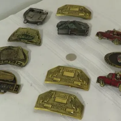 Collection of vintage novelty belt buckles featuring trucks, heavy machinery, and "Operating Engineer" designs, displayed on a...