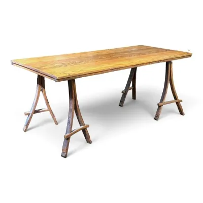 Sale Photo Thumbnail #83: Rustic wooden trestle dining table featuring a light oak-finished top supported by curved, dark-stained wooden sawhorse-style legs.