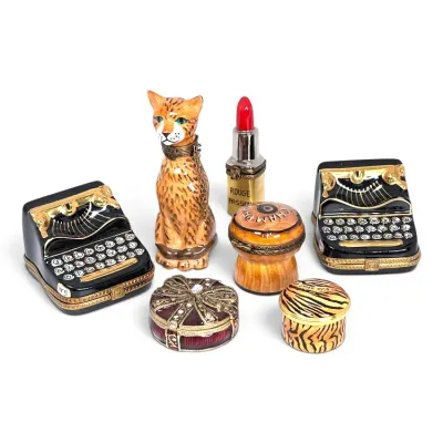 Sale Photo Thumbnail #142: Collection of seven vintage Limoges porcelain trinket boxes, featuring two typewriters, a cat, a lipstick, a champagne cork, and two round decorative boxes.