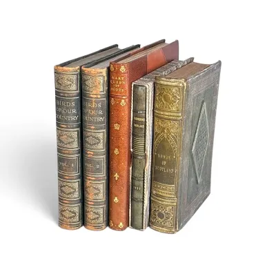 Sale Photo Thumbnail #141: Collection of five antique leather-bound books, including "Birds of Our Country" Volumes I and II, "Mary Queen of Scots," "Recording Scotland," and "Songs of Scotland," showing ornate gilt-embossed spines and age-appropriate wear.