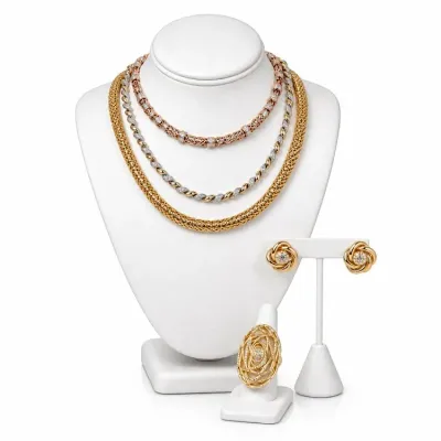 Sale Photo Thumbnail #13: Fine jewelry collection featuring three gold and diamond necklaces on a bust, paired with matching gold knot earrings and a statement wire-wrapped gold ring.