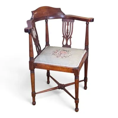 Sale Photo Thumbnail #106: Antique wooden corner chair featuring a curved backrest with pierced splats, turned legs with an X-stretcher, and a needlepoint seat cushion with a floral motif.