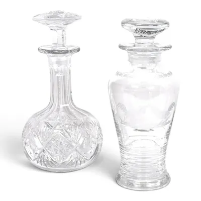 Sale Photo Thumbnail #198: Two vintage clear glass decanters with stoppers, featuring one with an intricate cut-glass starburst pattern and the other with an etched rooster motif.