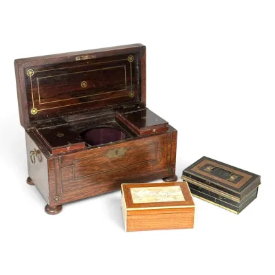 Sale Photo Thumbnail #221: Antique wooden tea caddy with brass inlay and bun feet, shown alongside a small carved wood box and a vintage metal cash box.