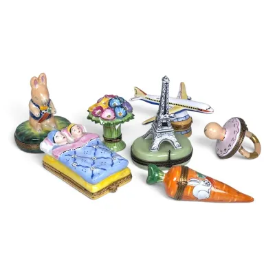 Sale Photo Thumbnail #134: Collection of seven hand-painted Limoges porcelain trinket boxes, featuring whimsical designs including a rabbit, children in bed, flowers, the Eiffel Tower, an airplane, a pacifier, and a carrot.