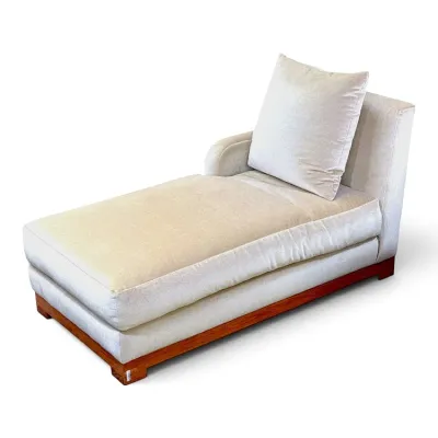 Sale Photo Thumbnail #117: Contemporary chaise lounge upholstered in a cream velvet fabric, featuring a wooden plinth base and a matching accent pillow.