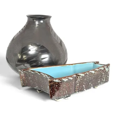 Sale Photo Thumbnail #208: San Ildefonso black-on-black pottery jar with geometric designs, paired with a mid-century modern footed ceramic planter featuring a textured brown exterior and turquoise blue interior glaze.
