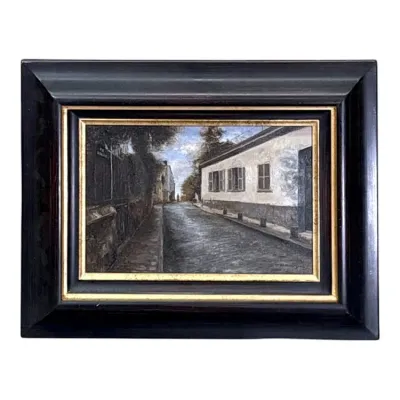 Sale Photo Thumbnail #67: Framed oil painting depicting a quiet European street scene, housed in a wide, dark wooden frame with a gold-painted inner border.