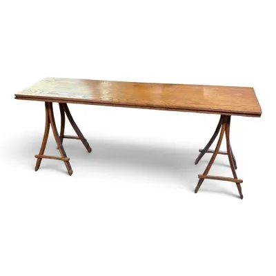 Sale Photo Thumbnail #93: Vintage oak trestle table featuring a long rectangular top with a warm wood grain finish, supported by curved, rustic-style wooden legs.
