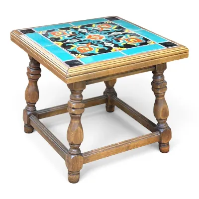 Sale Photo Thumbnail #99: Vintage Spanish Revival style wooden side table featuring a colorful inlaid ceramic tile top with turquoise, orange, and black patterns, supported by turned legs.