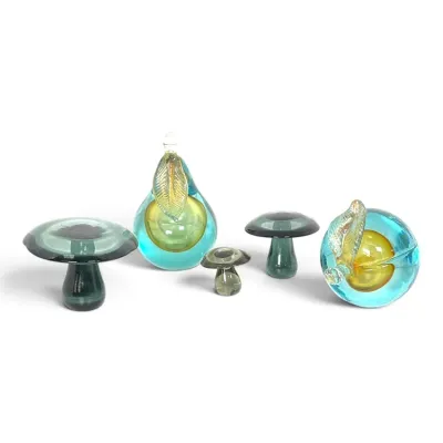 Sale Photo Thumbnail #175: Collection of mid-century modern art glass paperweights, including three mushrooms in shades of green and two fruit pieces featuring blue and amber glass with gold-flecked leaves.