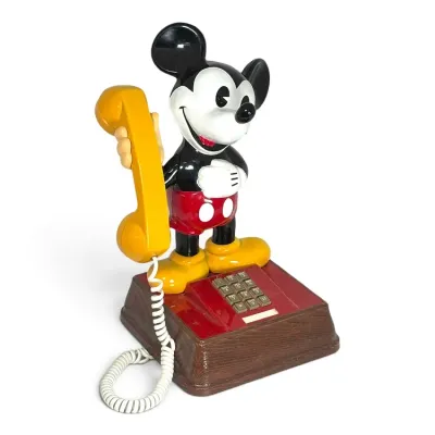 Sale Photo Thumbnail #218: Vintage Mickey Mouse push-button landline telephone by ATC, featuring a faux-woodgrain base and yellow handset, circa 1970s.