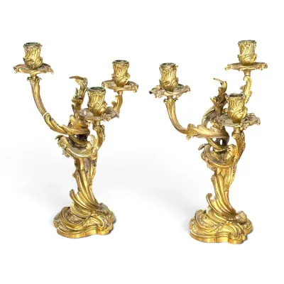 Sale Photo Thumbnail #162: Pair of ornate French Rococo style gilt bronze three-light candelabra, featuring swirling acanthus leaf and floral motifs.
