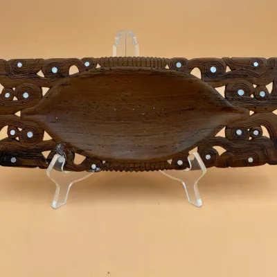 Sale Photo Thumbnail #75: Hand-carved Maori waka huia (treasure box) lid or decorative wooden tray, featuring intricate scrollwork and inlaid paua shell details.