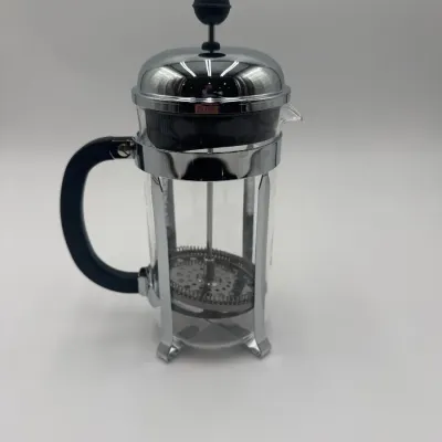 Sale Photo Thumbnail #106: Classic Bodum French press coffee maker featuring a clear glass beaker, chrome-plated steel frame and lid, and a black plastic handle.