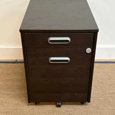 Sale Photo Thumbnail #129: Modern dark brown wood-grain mobile filing cabinet featuring two drawers with silver-toned handles, a combination lock, and caster wheels.