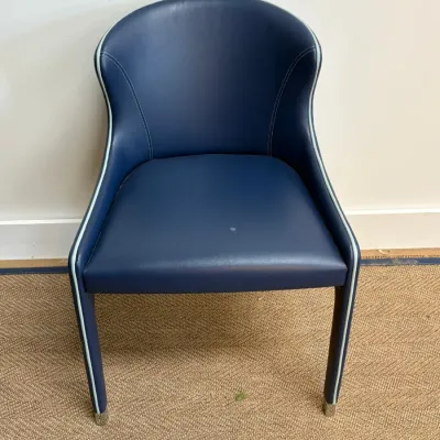 Sale Photo Thumbnail #127: Contemporary blue leather dining or accent chair featuring a curved back, light blue piping detail, and leather-wrapped legs with metal glides.
