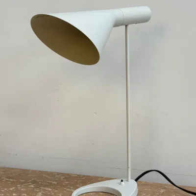 Sale Photo Thumbnail #155: Mid-century modern white metal desk lamp featuring a cone-shaped shade and a circular open-ring base.