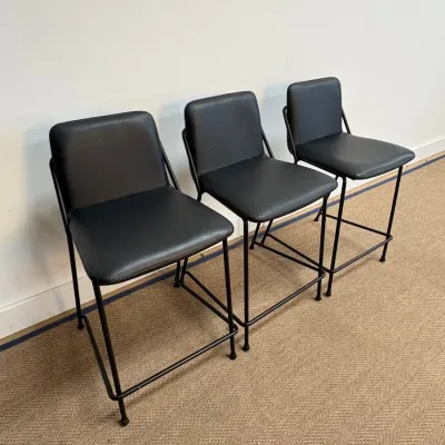 Sale Photo Thumbnail #42: Trio of modern counter-height barstools featuring black faux leather upholstery and matching black metal frames.
