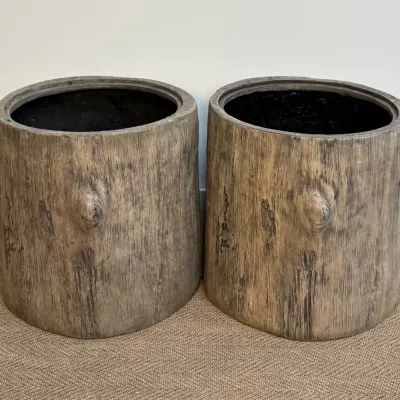 Sale Photo Thumbnail #44: Pair of faux bois planters designed to resemble natural tree stumps with realistic bark texture and knot details.