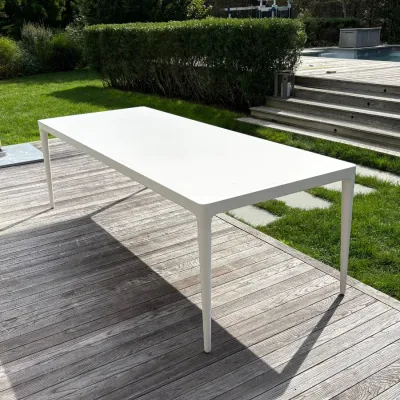 Sale Photo Thumbnail #10: Modern minimalist white outdoor dining table with tapered legs, shown on a wooden deck.
