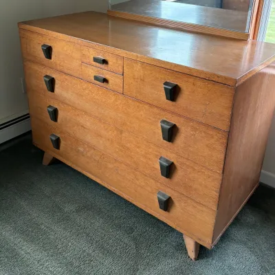 Sale Photo Thumbnail #53: Mid-century modern blonde wood dresser featuring distinctive dark, angular drawer pulls and tapered legs, complete with an attached mirror.
