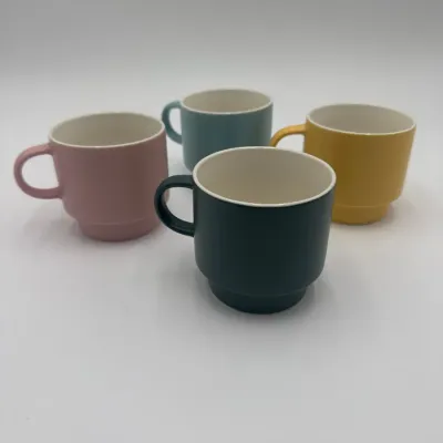 Sale Photo Thumbnail #77: Set of four mid-century modern style stacking ceramic mugs in matte pink, blue, yellow, and dark green with white interiors.
