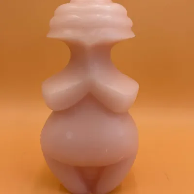 Sale Photo Thumbnail #73: Pink wax candle shaped like the Venus of Willendorf fertility figure, featuring a stylized female form with a single wick at the top.