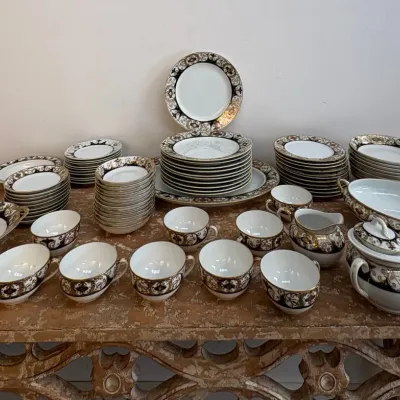 Sale Photo Thumbnail #110: Vintage fine china dinnerware set featuring an ornate black and gold scrollwork border, including plates, bowls, teacups, a lidded sugar bowl, and serving platters.