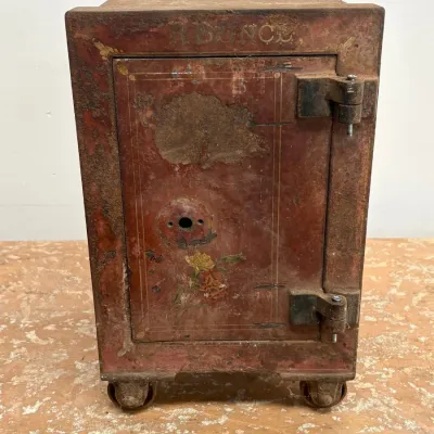 Sale Photo Thumbnail #172: Antique cast iron floor safe on wheels, featuring a heavily weathered red painted finish with faded floral stenciling and the name "R. BUNCH" visible at the top.