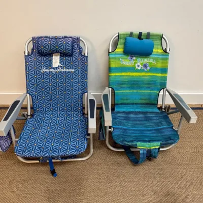 Sale Photo Thumbnail #147: Pair of Tommy Bahama folding backpack beach chairs, one featuring a blue geometric pattern and the other a green and blue striped design, both with integrated headrest pillows.