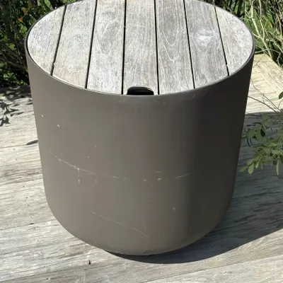 Sale Photo Thumbnail #7: Modern cylindrical outdoor side table featuring a weathered wood slat top and a dark brown composite base with minor scuffs.