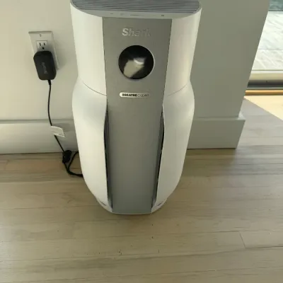 Sale Photo Thumbnail #19: Shark Breathe Clear air purifier in white and silver, plugged in and sitting on a light wood floor.