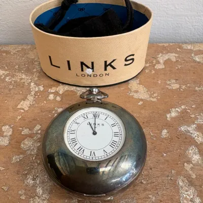 Sale Photo Thumbnail #145: Links of London sterling silver pocket watch with Roman numerals, accompanied by its original presentation box and drawstring pouch.