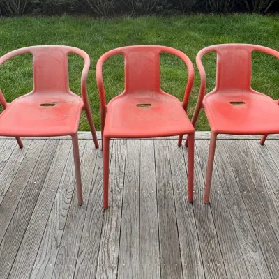 Sale Photo Thumbnail #25: Trio of modern molded plastic armchairs in a coral pink hue, showing some weathering and fading from outdoor use.