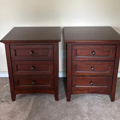 Sale Photo Thumbnail #52: Pair of contemporary cherry-finished wood nightstands, each featuring three drawers with dark metal knob pulls.