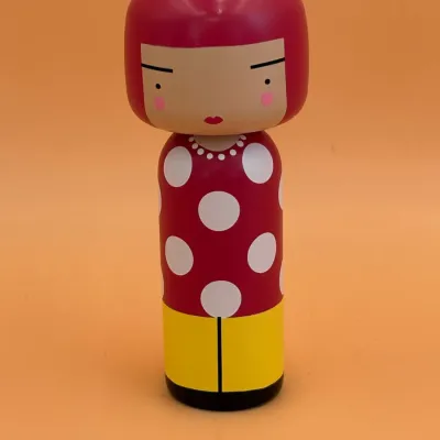 Sale Photo Thumbnail #76: Lucie Kaas wooden kokeshi doll depicting artist Yayoi Kusama, featuring her signature red bob, polka dot dress, and yellow pants.
