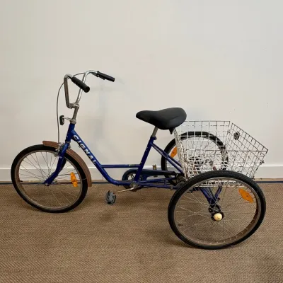 Sale Photo Thumbnail #115: Vintage Signal three-wheel adult tricycle in blue, featuring a large white wire rear cargo basket, high-rise handlebars, and a padded black seat.