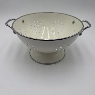Sale Photo Thumbnail #111: Vintage-style white enamel colander with a pedestal base and chrome-finished handles and rim.