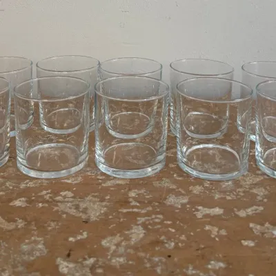 Sale Photo Thumbnail #174: Set of ten clear glass lowball tumblers with a simple, modern design, displayed on a rustic wooden surface.