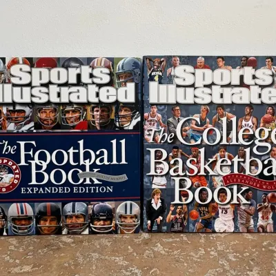Sale Photo Thumbnail #90: Two Sports Illustrated hardcover books, including "The Football Book Expanded Edition" and "The College Basketball Book," featuring illustrated covers of sports players.