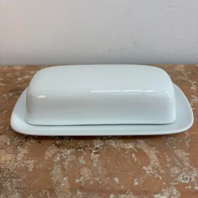 Sale Photo Thumbnail #169: Simple white ceramic butter dish with matching lid, showing a clean, minimalist design.