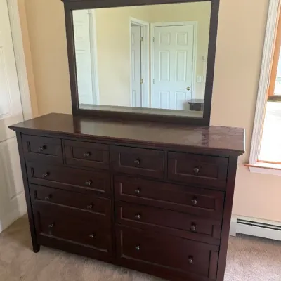 Sale Photo Thumbnail #49: Contemporary dark wood dresser featuring ten drawers with simple round knobs and a matching large rectangular wall-mounted mirror.