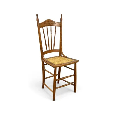Sale Photo Thumbnail #200: Antique oak dining chair featuring a pressed-back design with carved details, spindle backrest, and a woven cane seat.